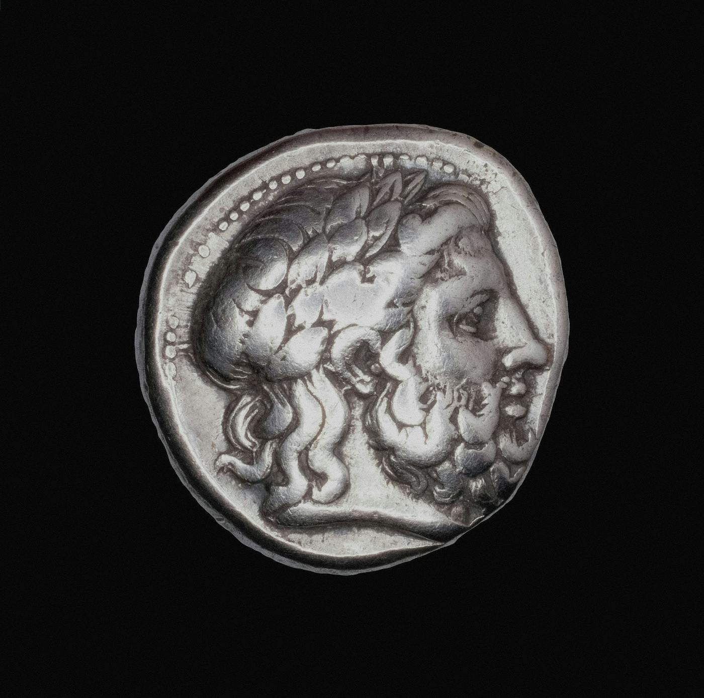 An ancient Greek coin with the head of Zeus on it