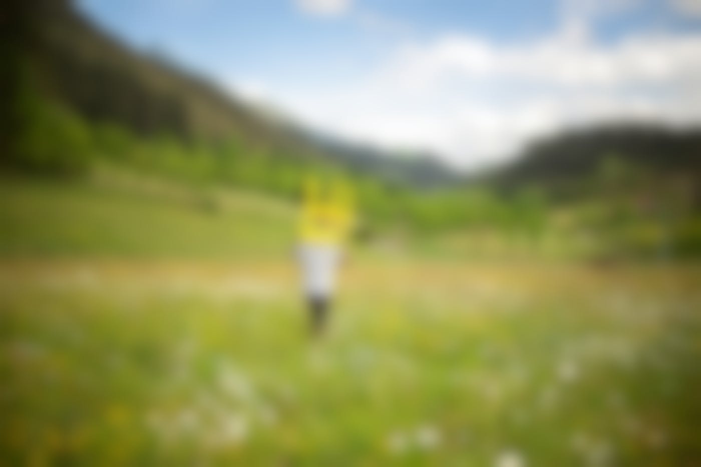 A man carrying a yellow chair into the middle of a field.