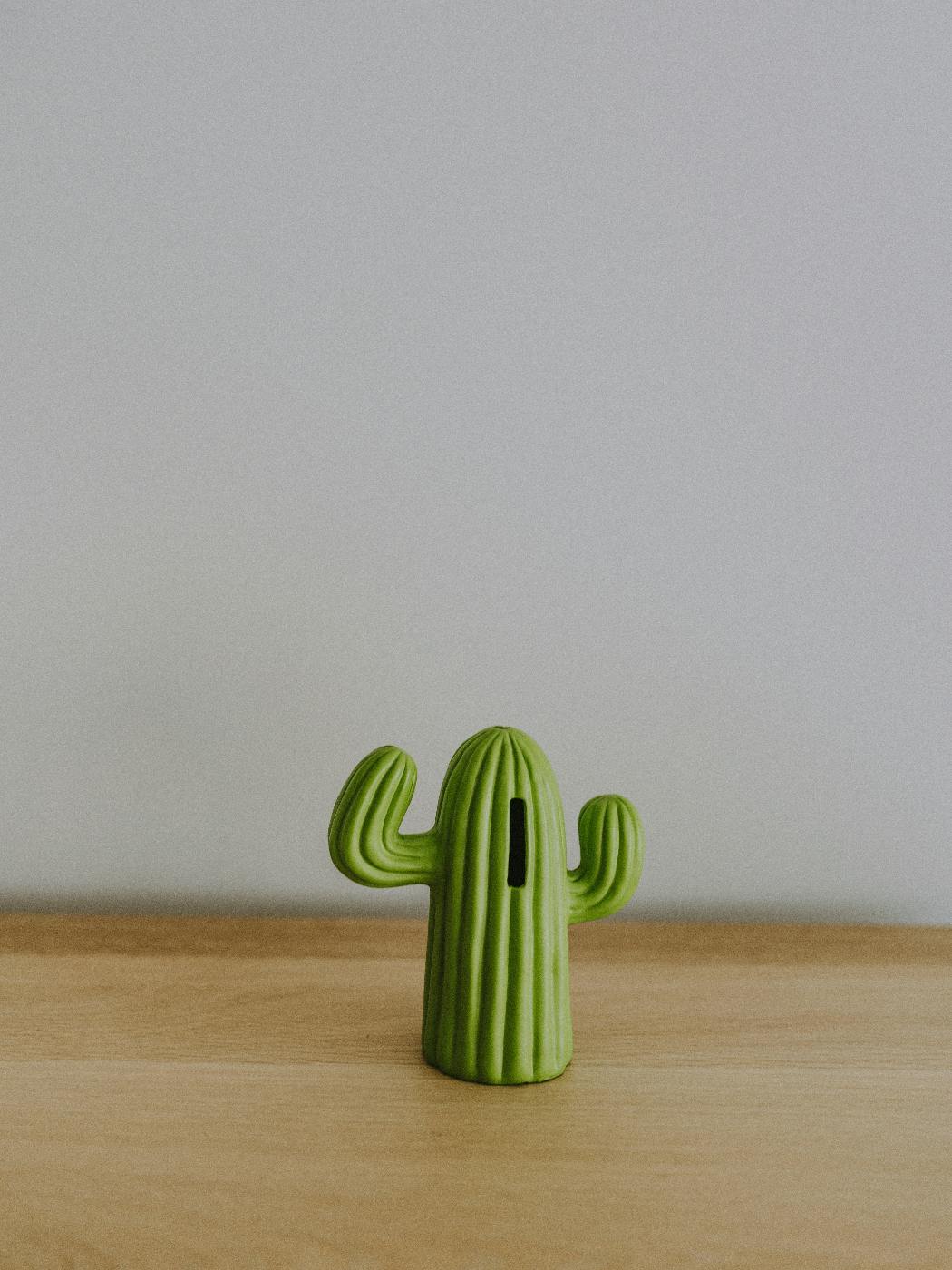 A small cactus shaped coin bank on a table