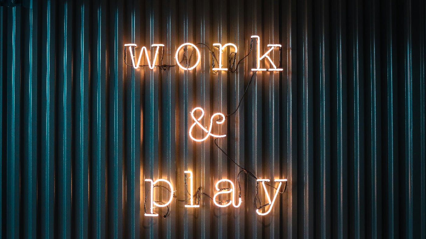 An orange neon sign reading Work & Play