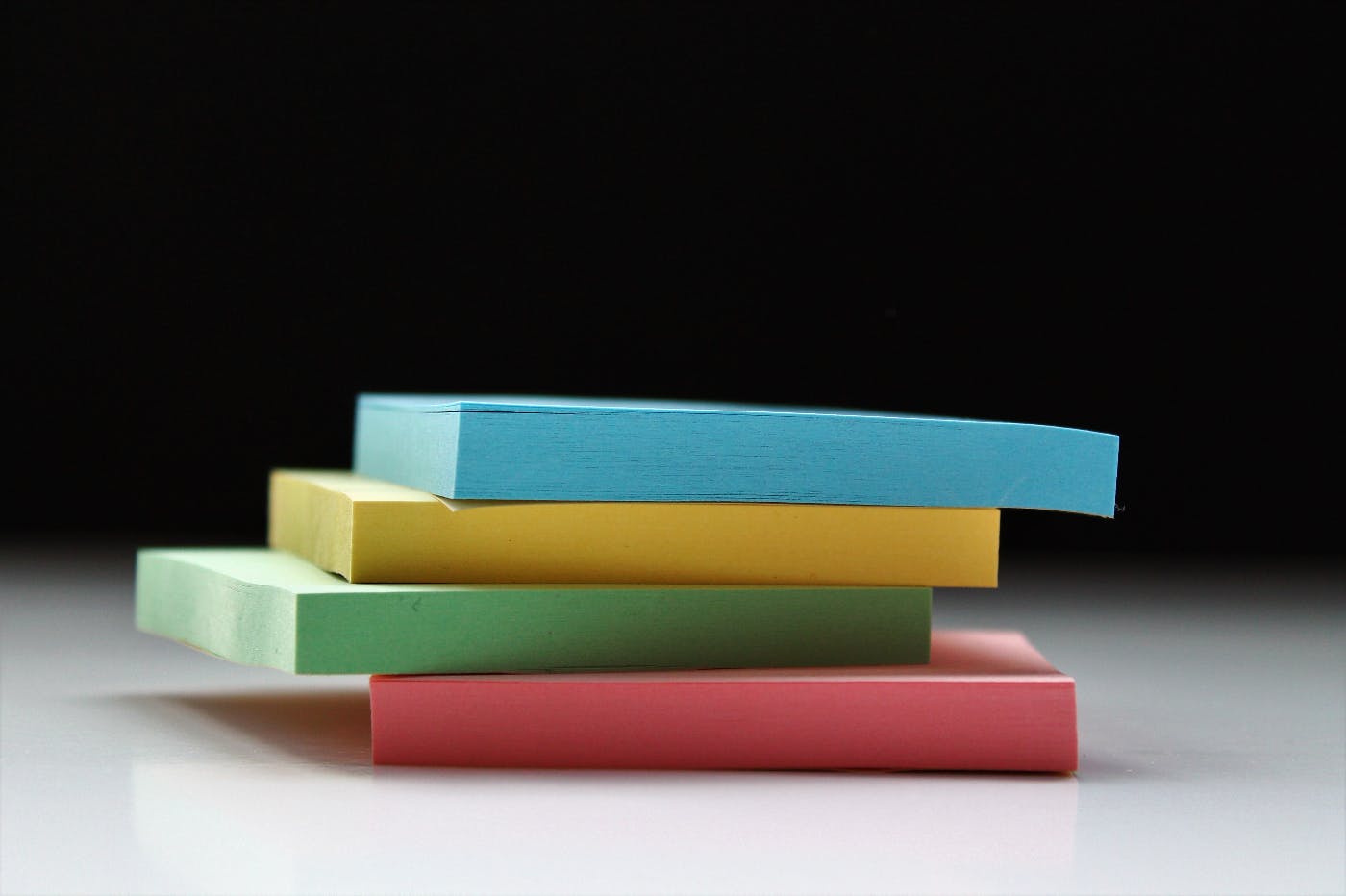 a stack of 4 packs of sticky notes in blue, yellow, green and red