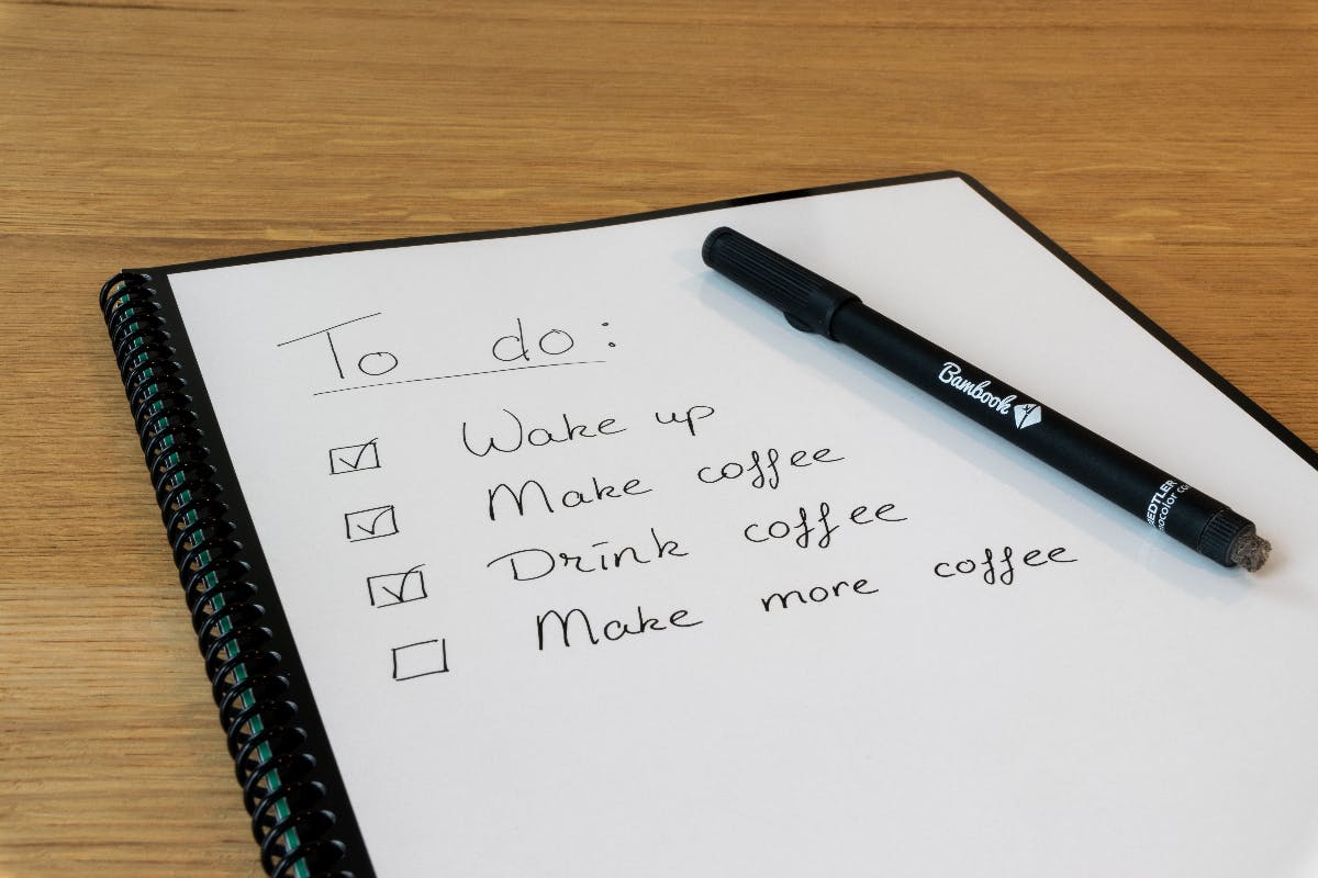 A notebooks with a pen and a To Do list: Wake up, make coffee, drink coffee, make ore coffee.