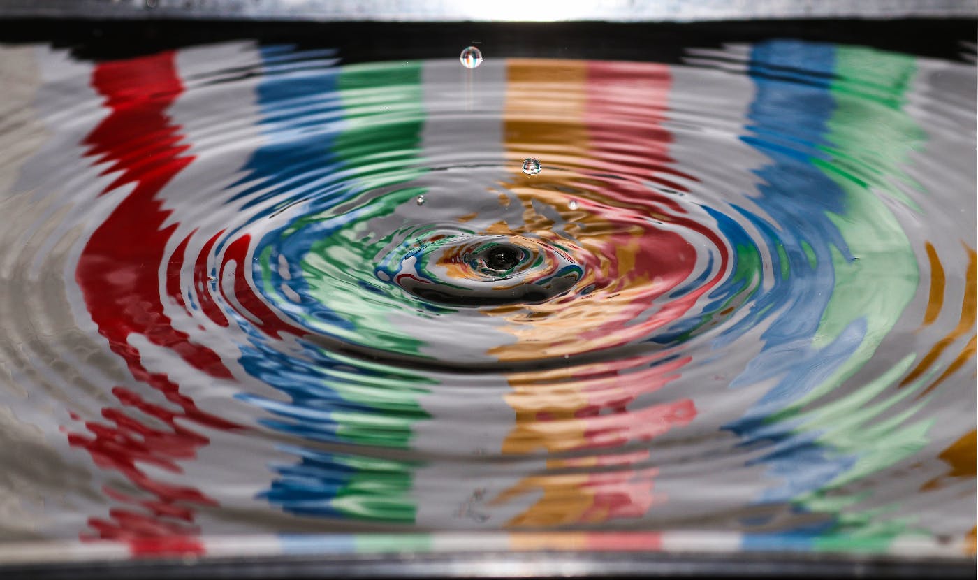 water over a striped cloth with a drop falling into it creating waves