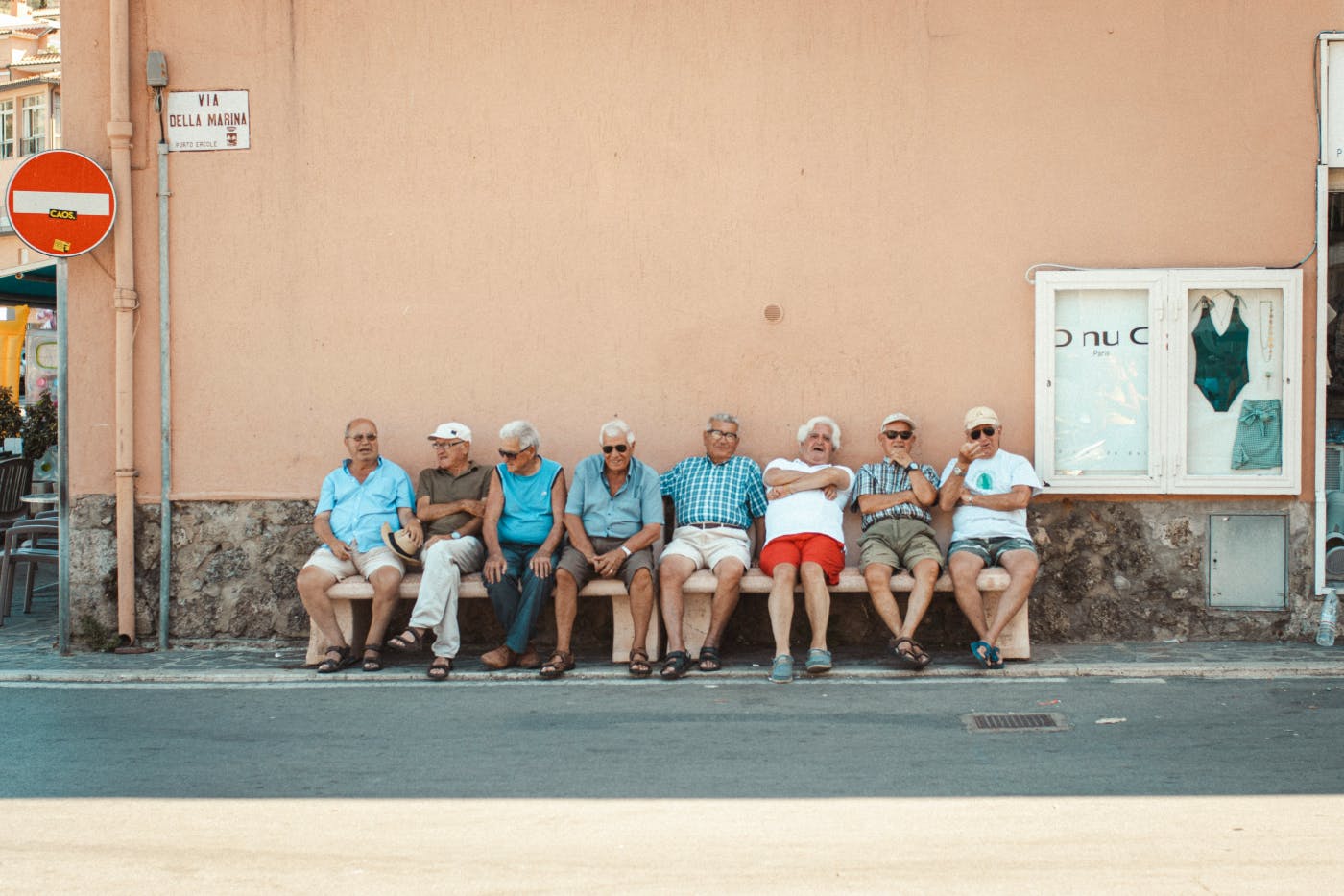 Eight older men sitting on a bench in the Via Della Marina