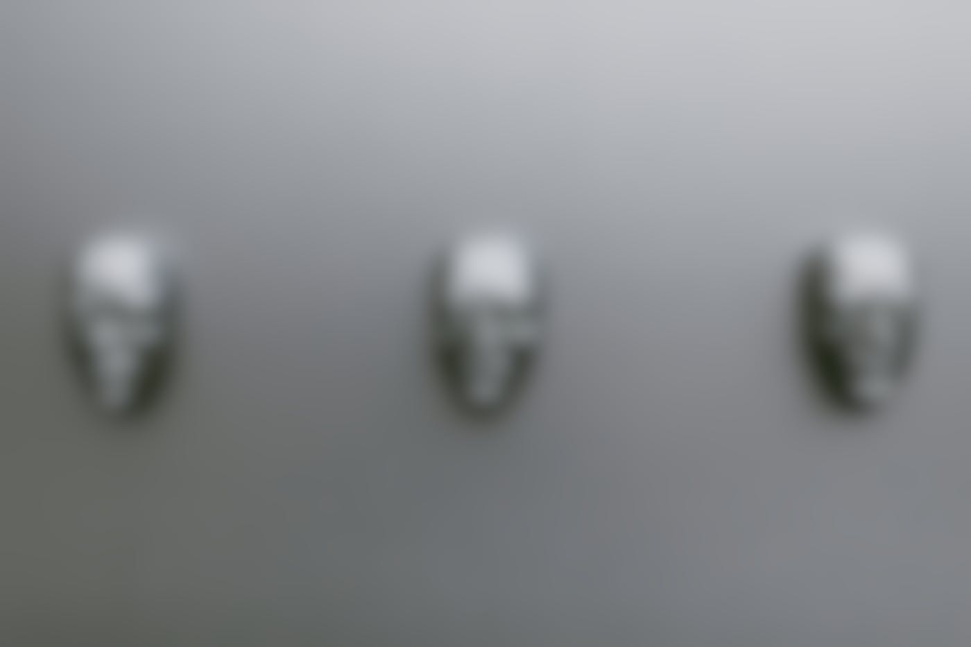 Three silver masks of the same man but in different emotional states