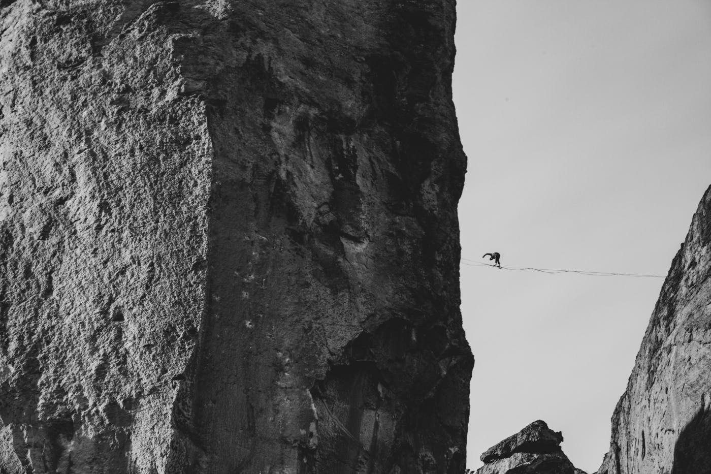 A person on a tightrope high above some rocks