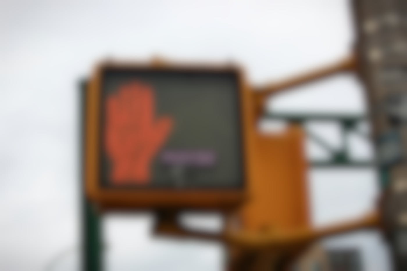 The red stop hand of a traffic light with a small sticker reading 'maybe' next to it
