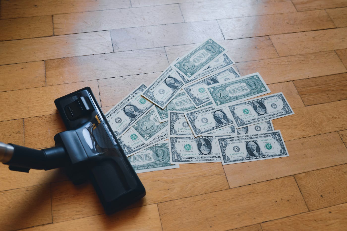 One dollar bills being sucked up by a vacuum cleaner