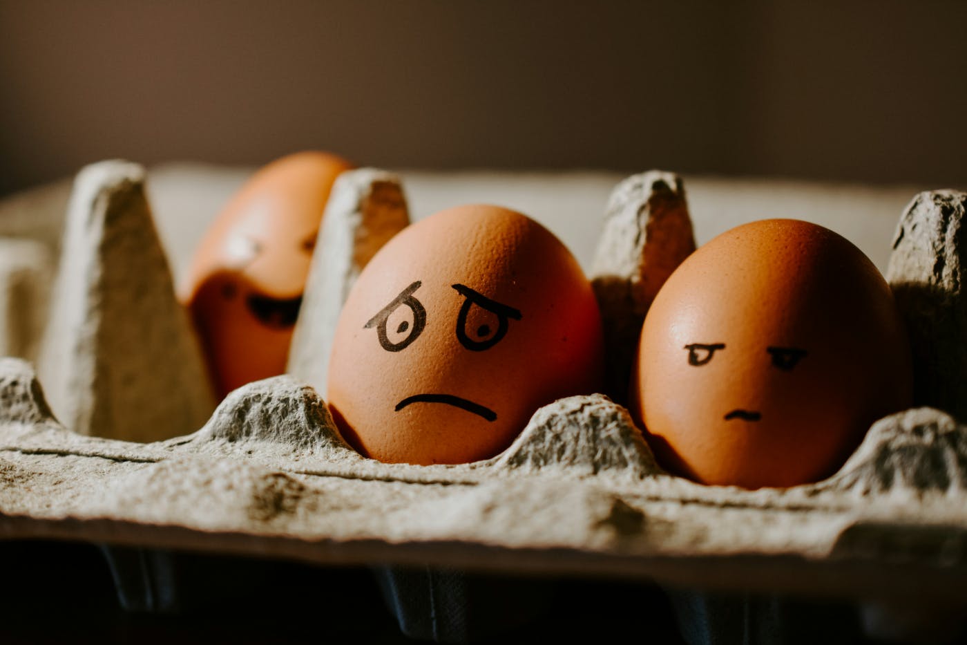 Eggs in a carton with emotional expressions drawn on them