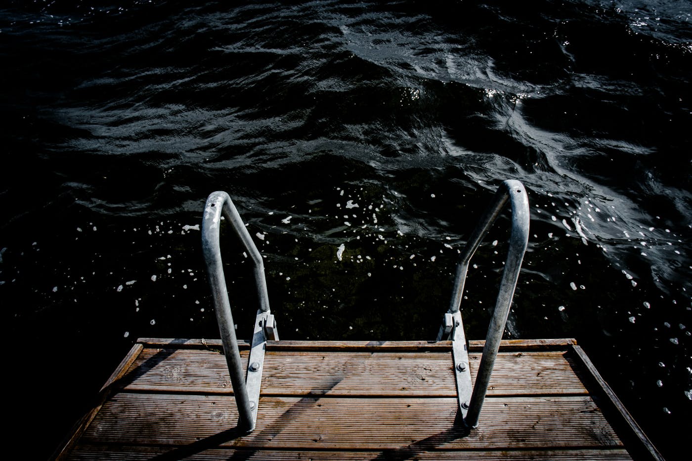 A dock with railings leading into very dark water