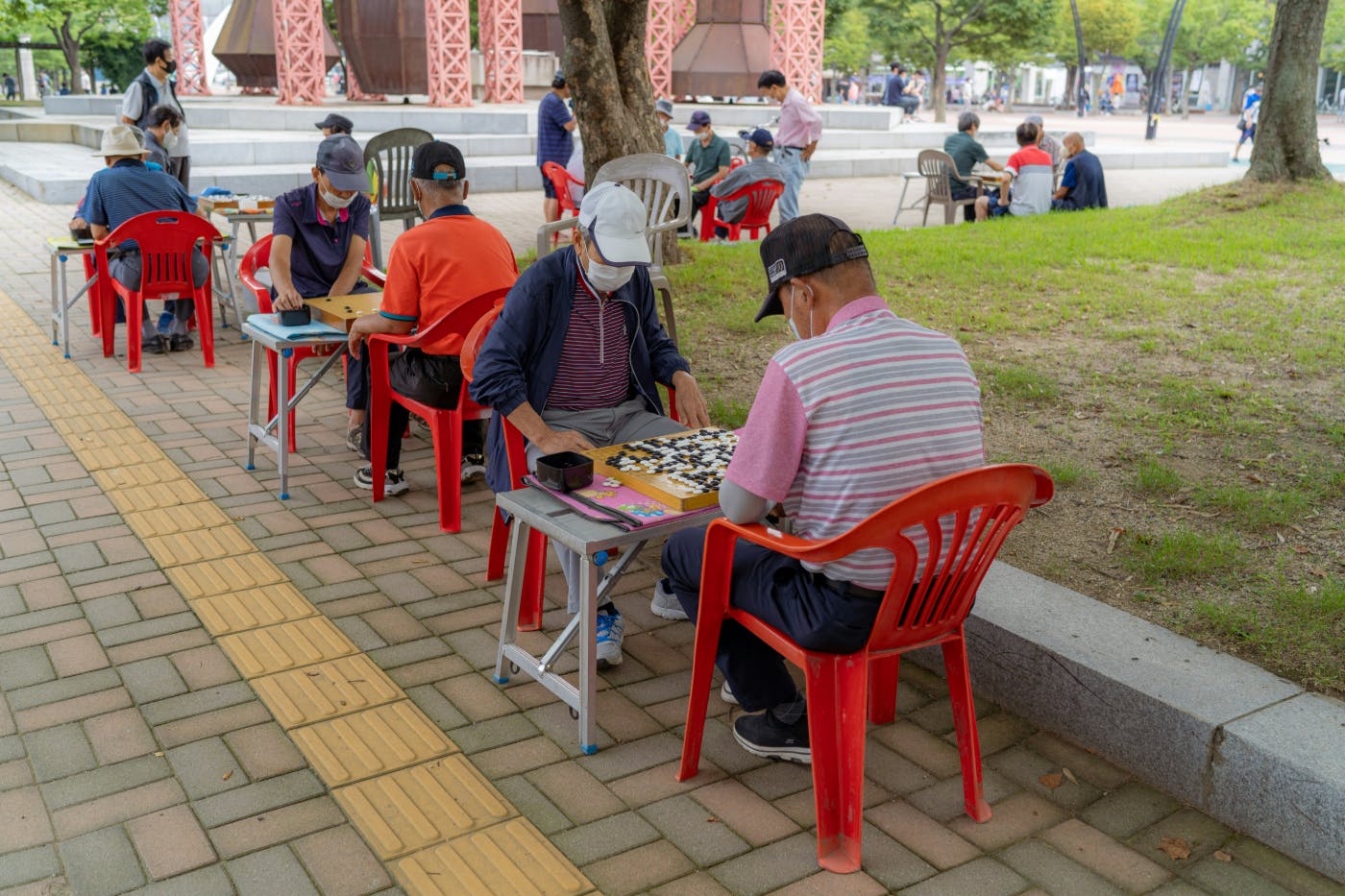 People outside, sitting at tables, playing GO