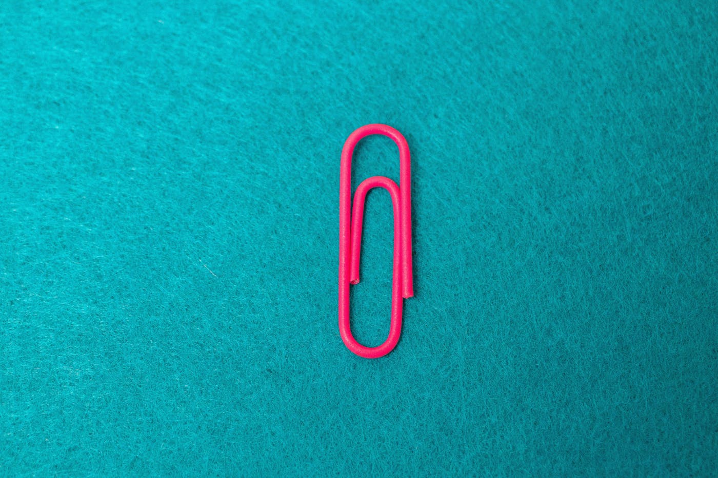 A pink paper clip on a blue background