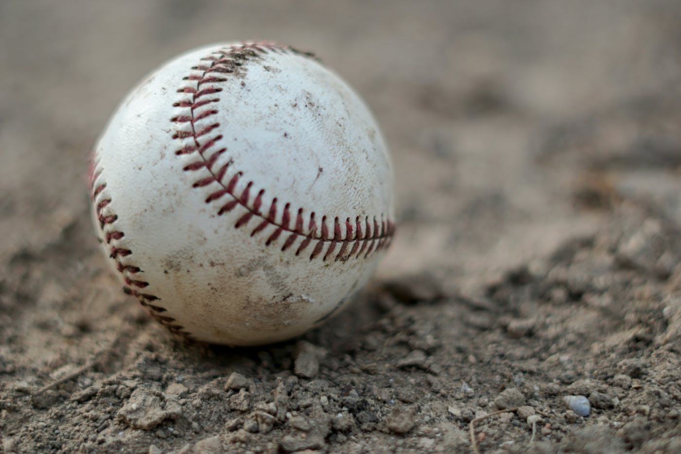 W well used baseball sitting in the dirt