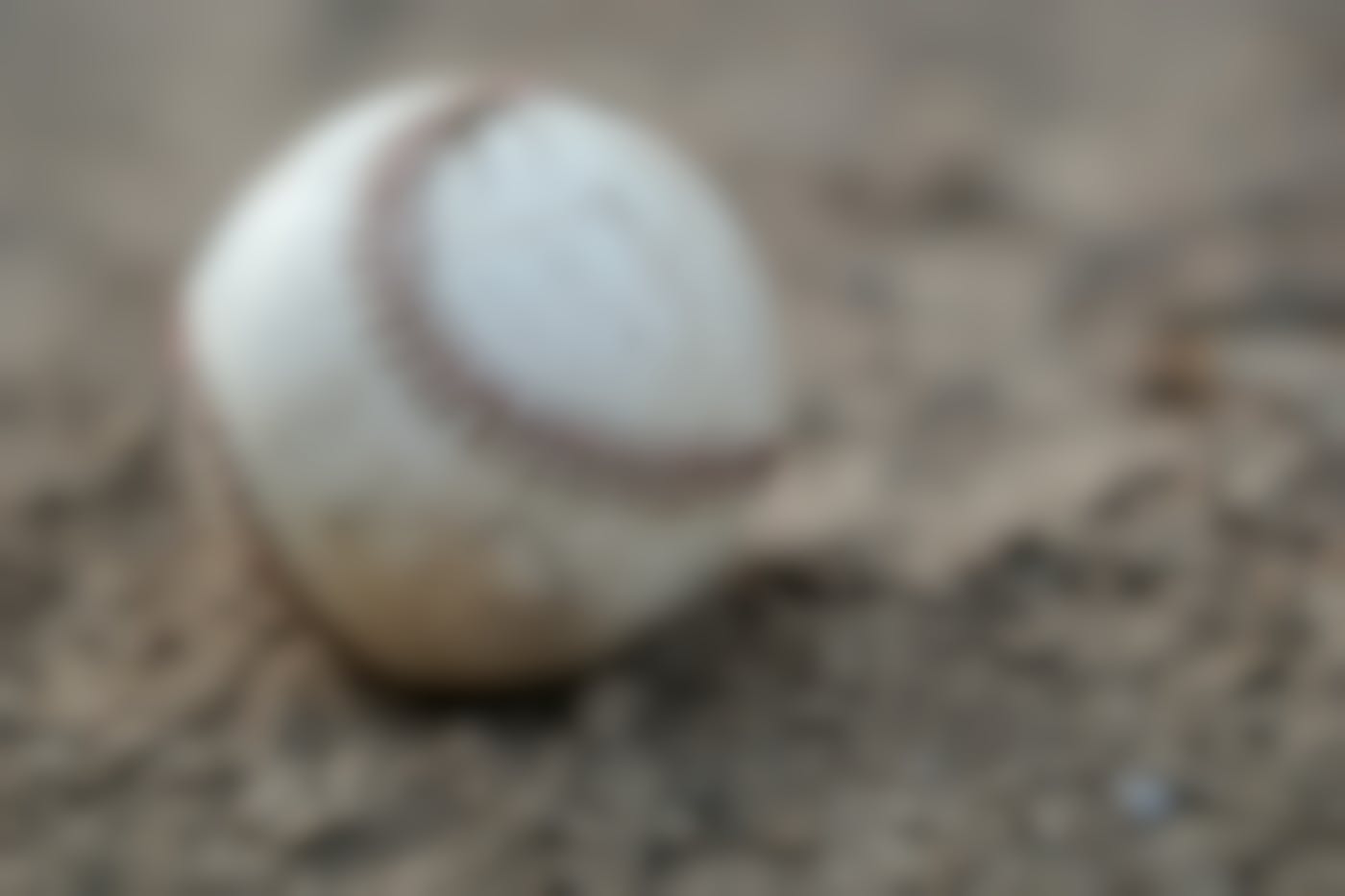 W well used baseball sitting in the dirt