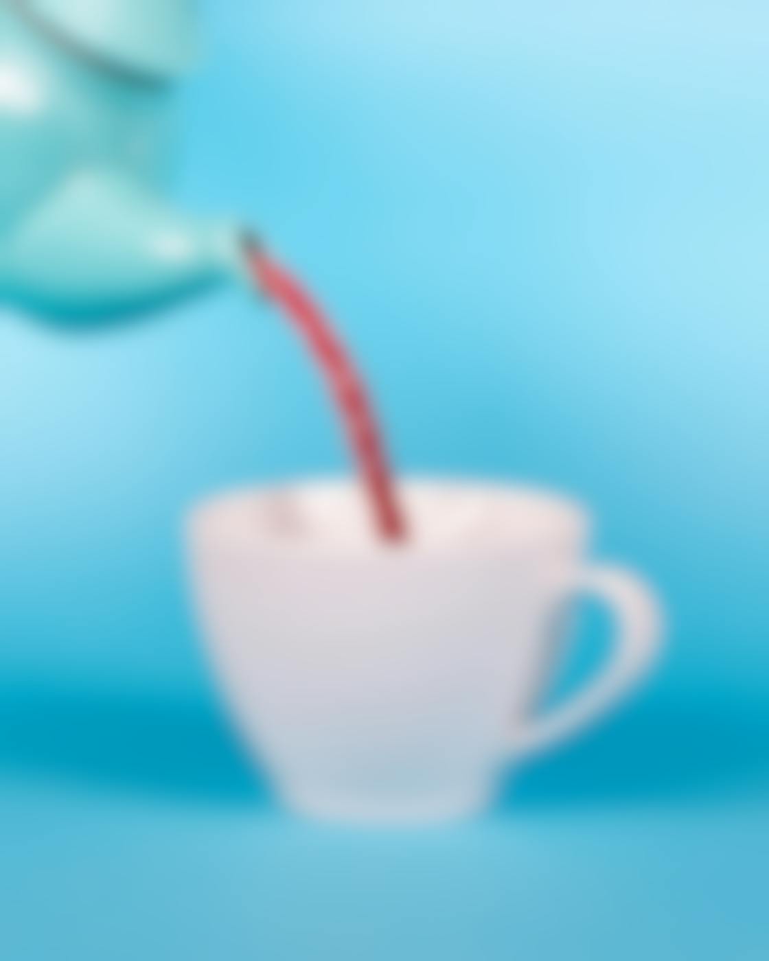 A blue tea pot pouring a red Twizzler into a white cup
