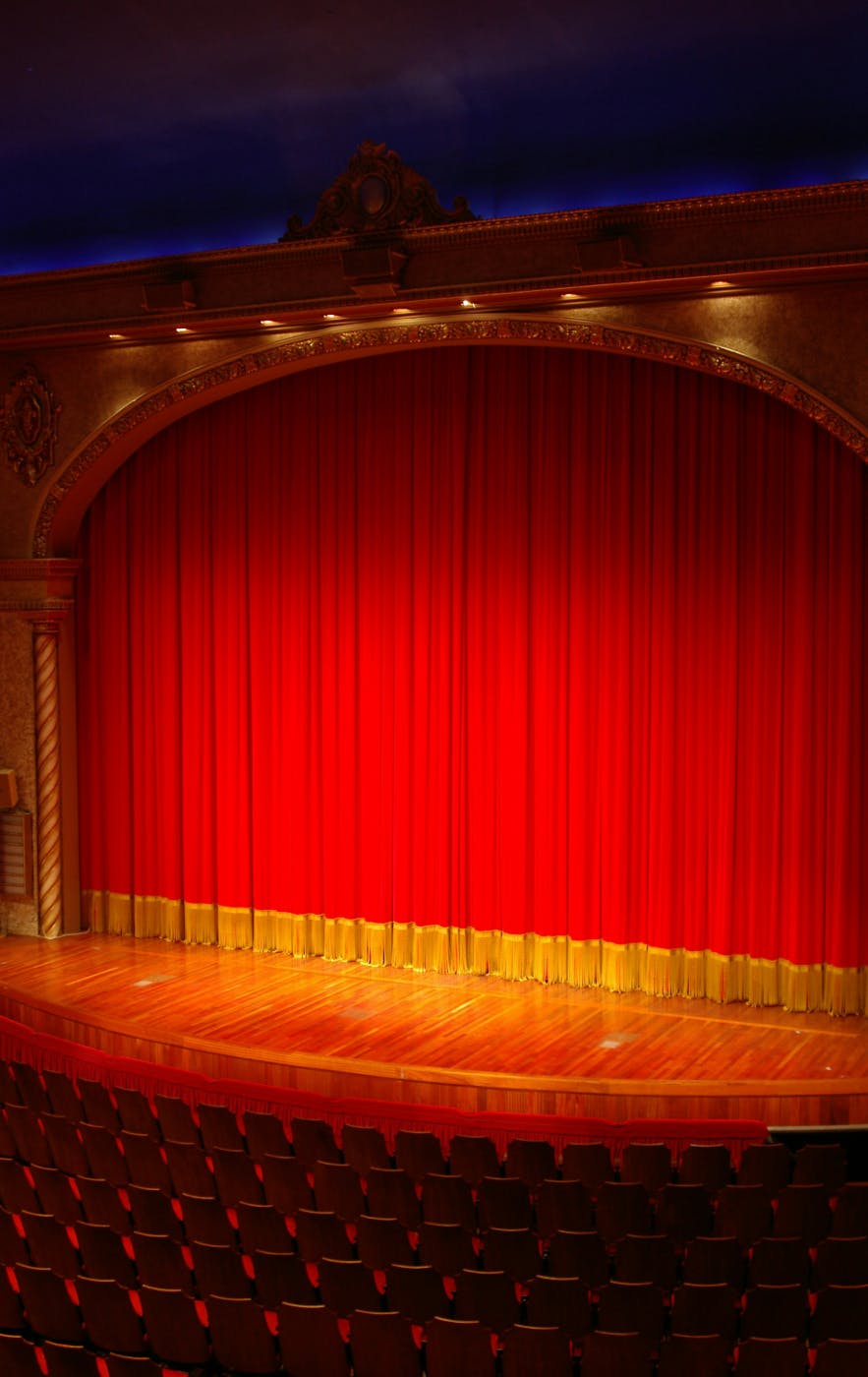 A red and yellow grand drape on an empty stage