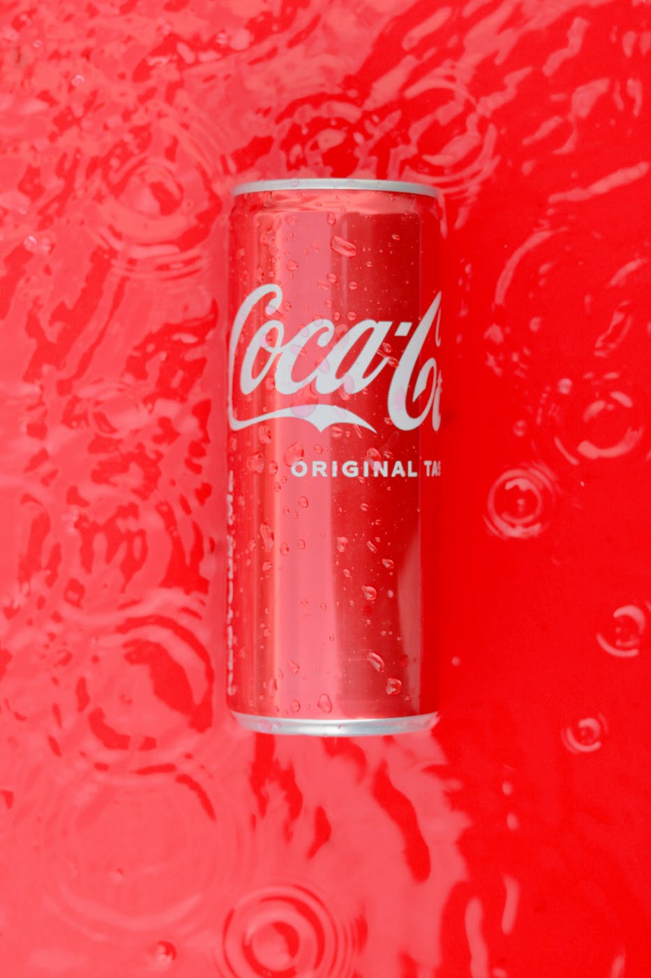 A can of Coke on a red, wet background