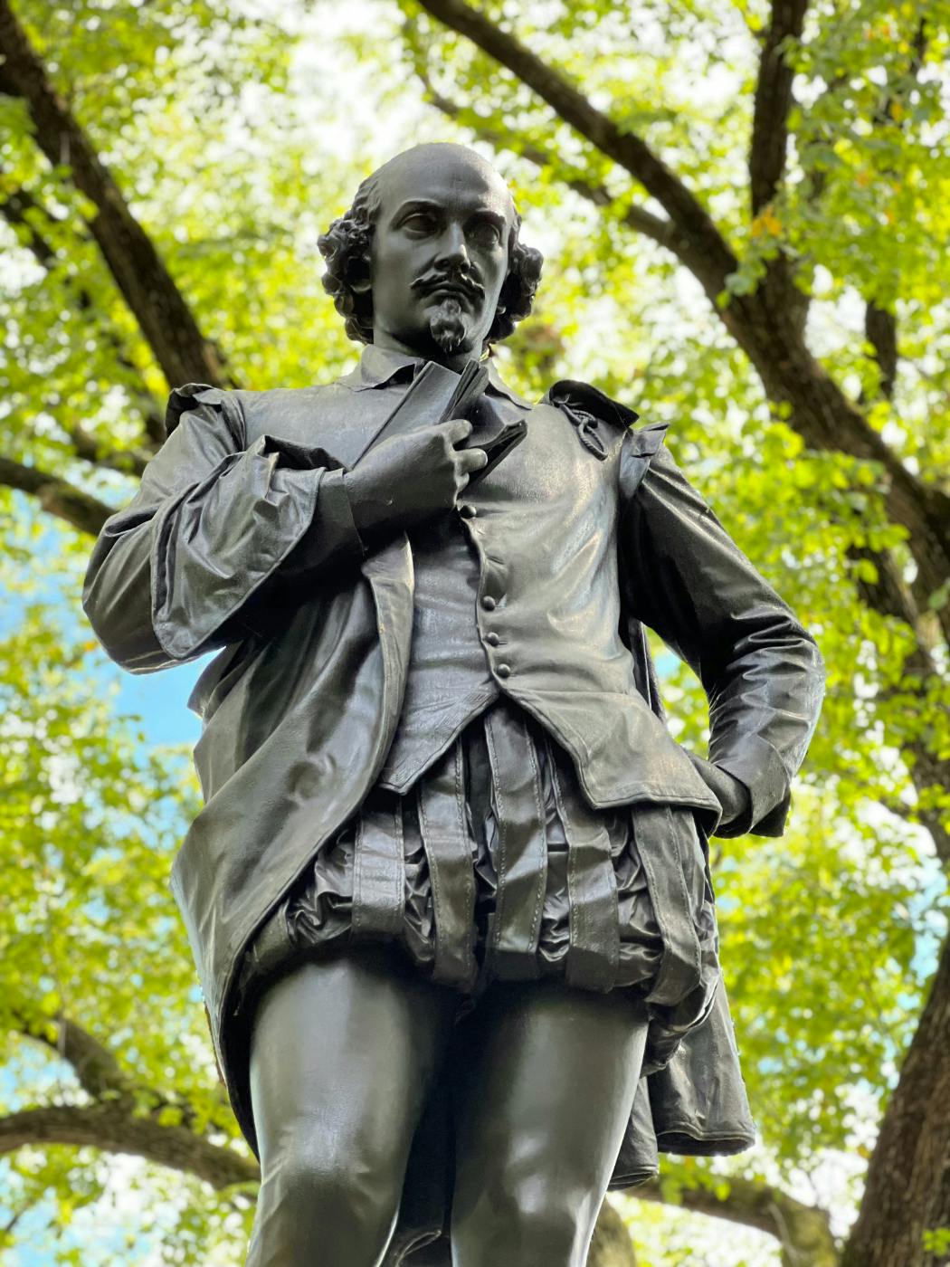 A statue of Shakespeare in a park