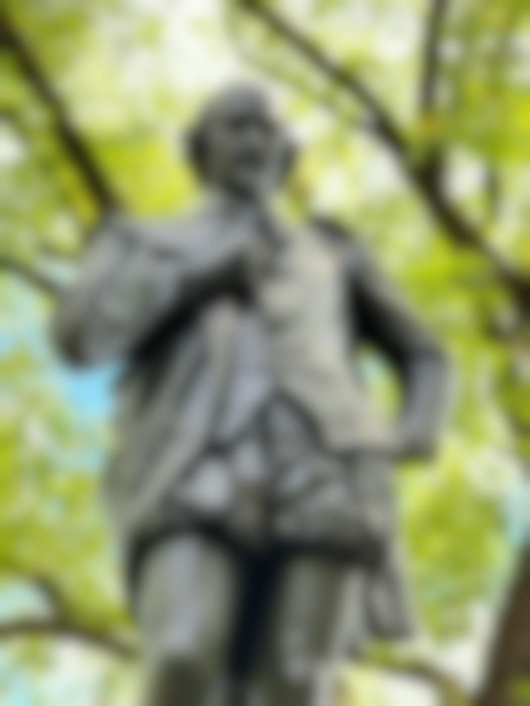 A statue of Shakespeare in a park