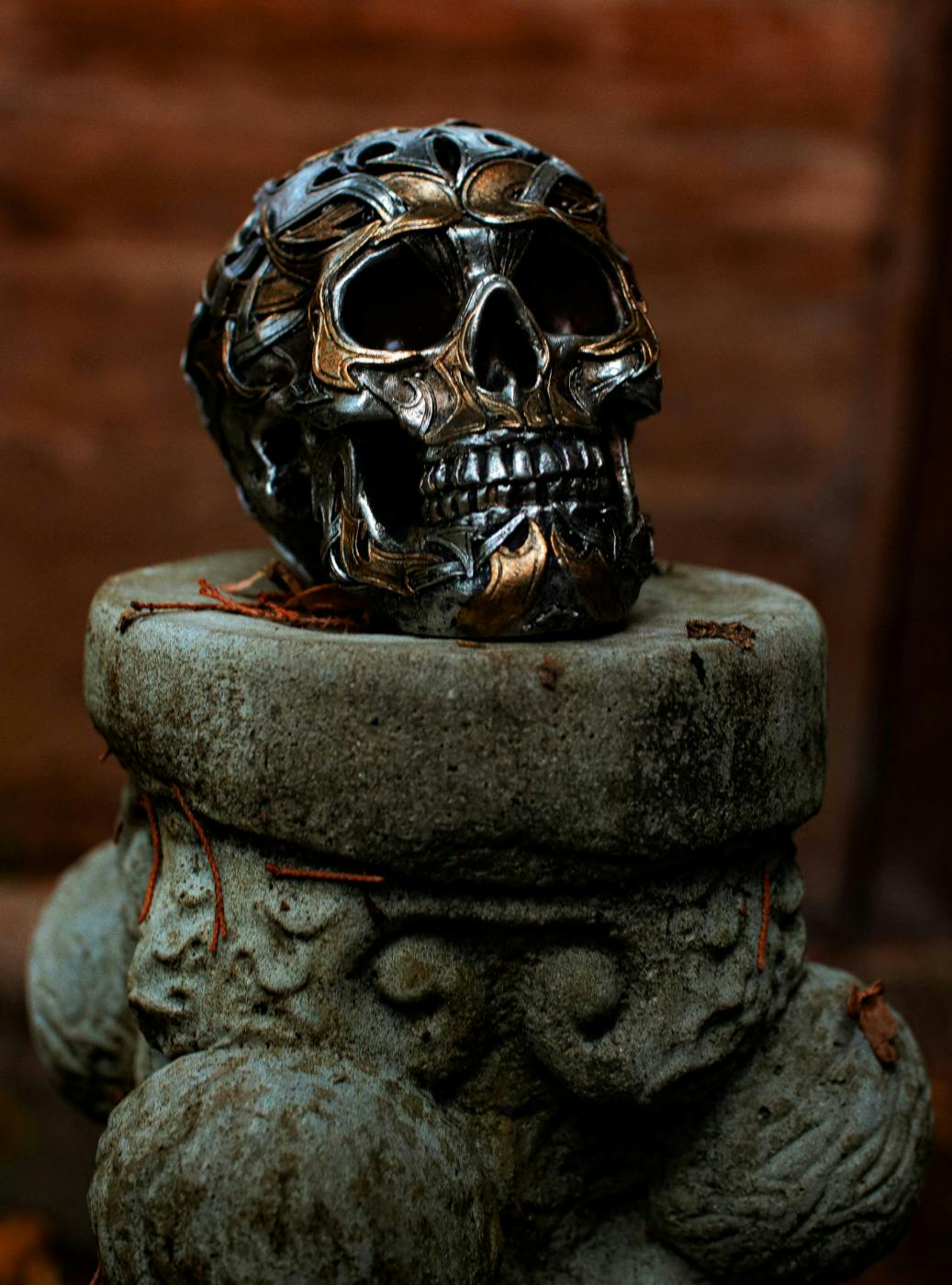 A black and gold gilded human skull on a plinth
