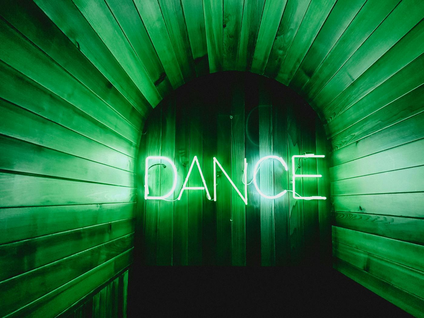 A small room with a green neon sign reading DANCE