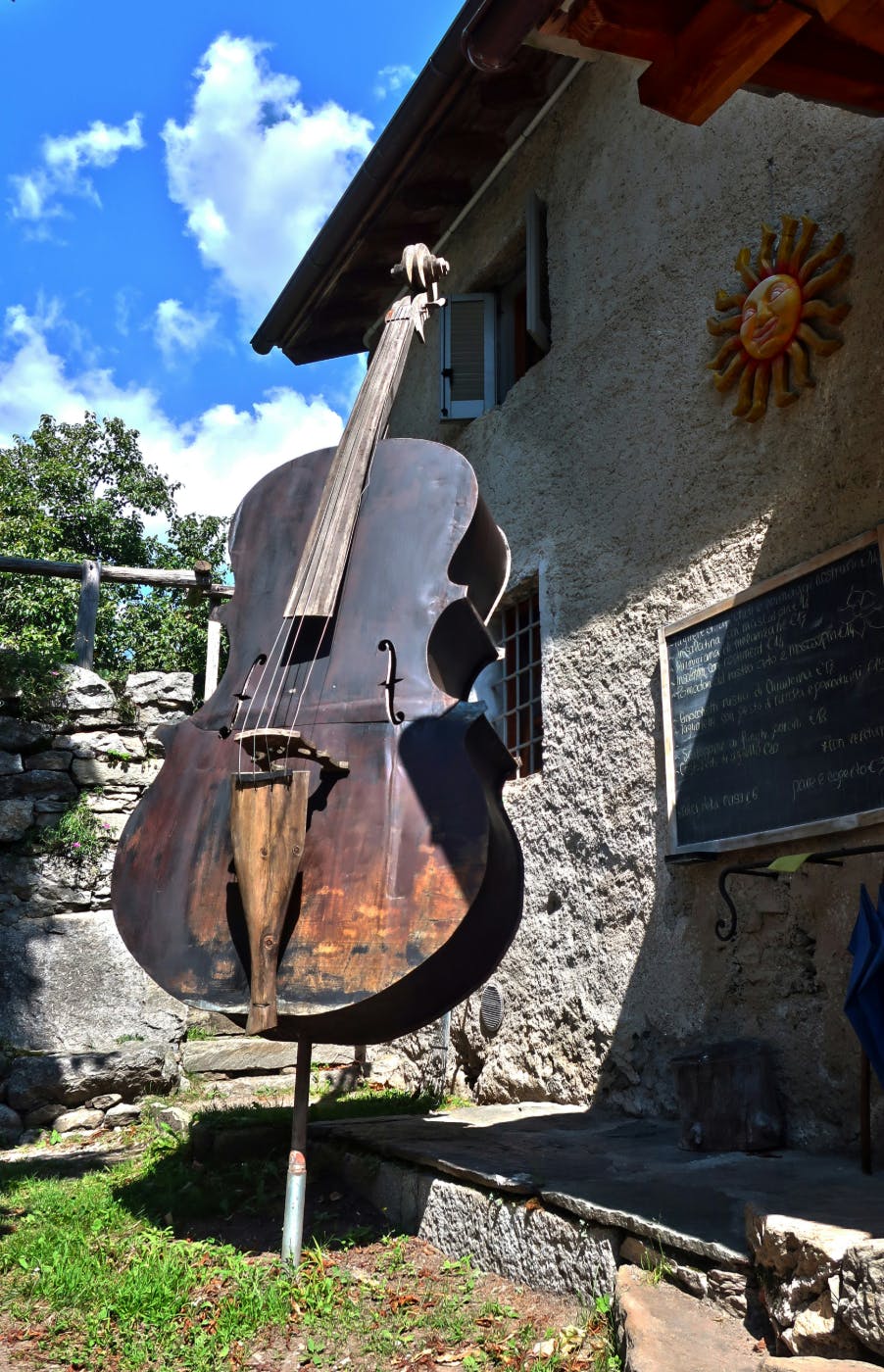 An old warn upright bass sitting outside in the sun