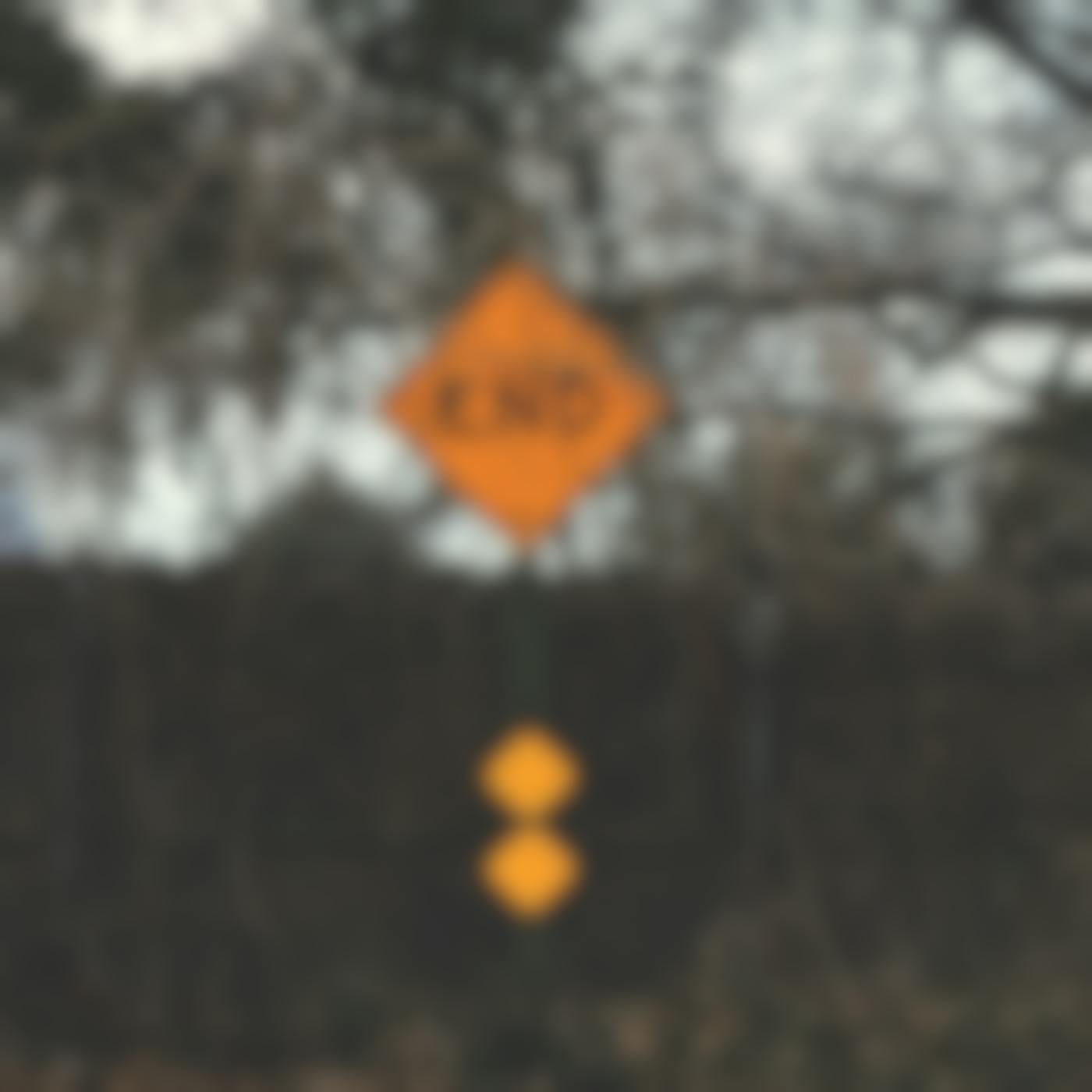 A yellow sign reading END in front of a fence and some shrubs