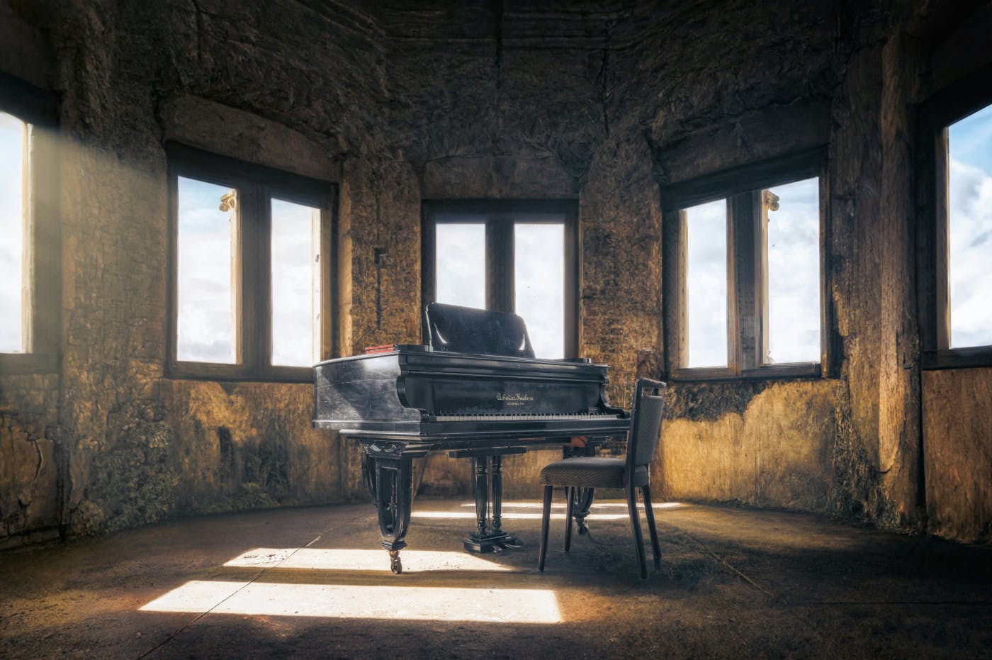 An old, dusty baby grand piano and chair in a dilapidated room.