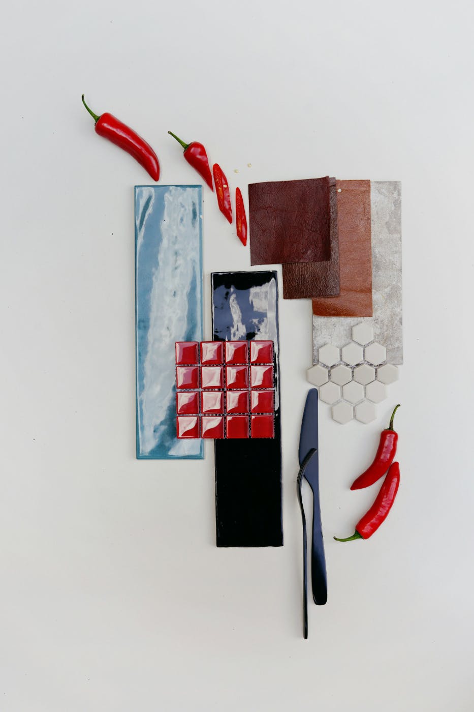 A mood board with swatches of material, leather, red tile and red chili peppers