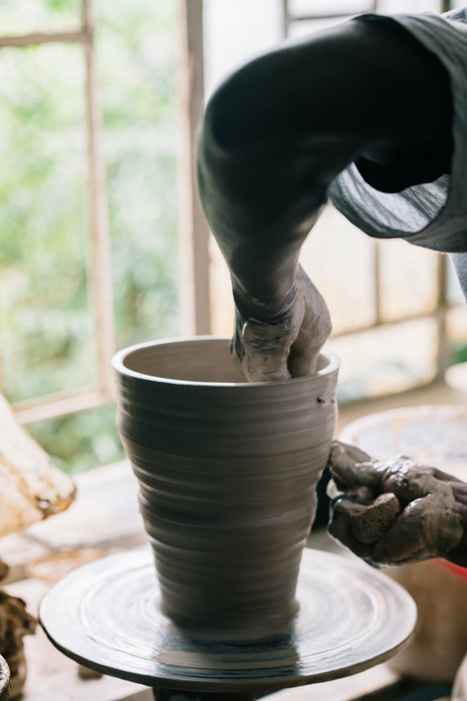 A person working clay on a potter's wheel