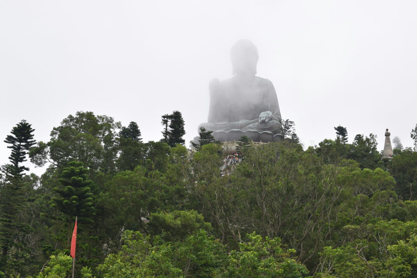 A giant seated Buddha statue in the mist above the trees