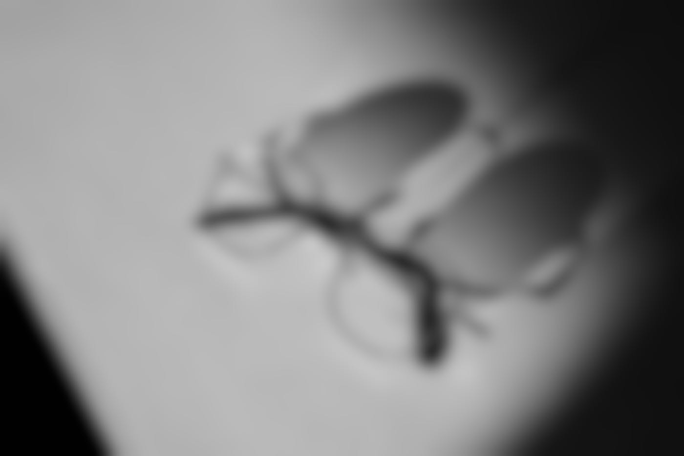 A pair of glasses on a table with a long shadow