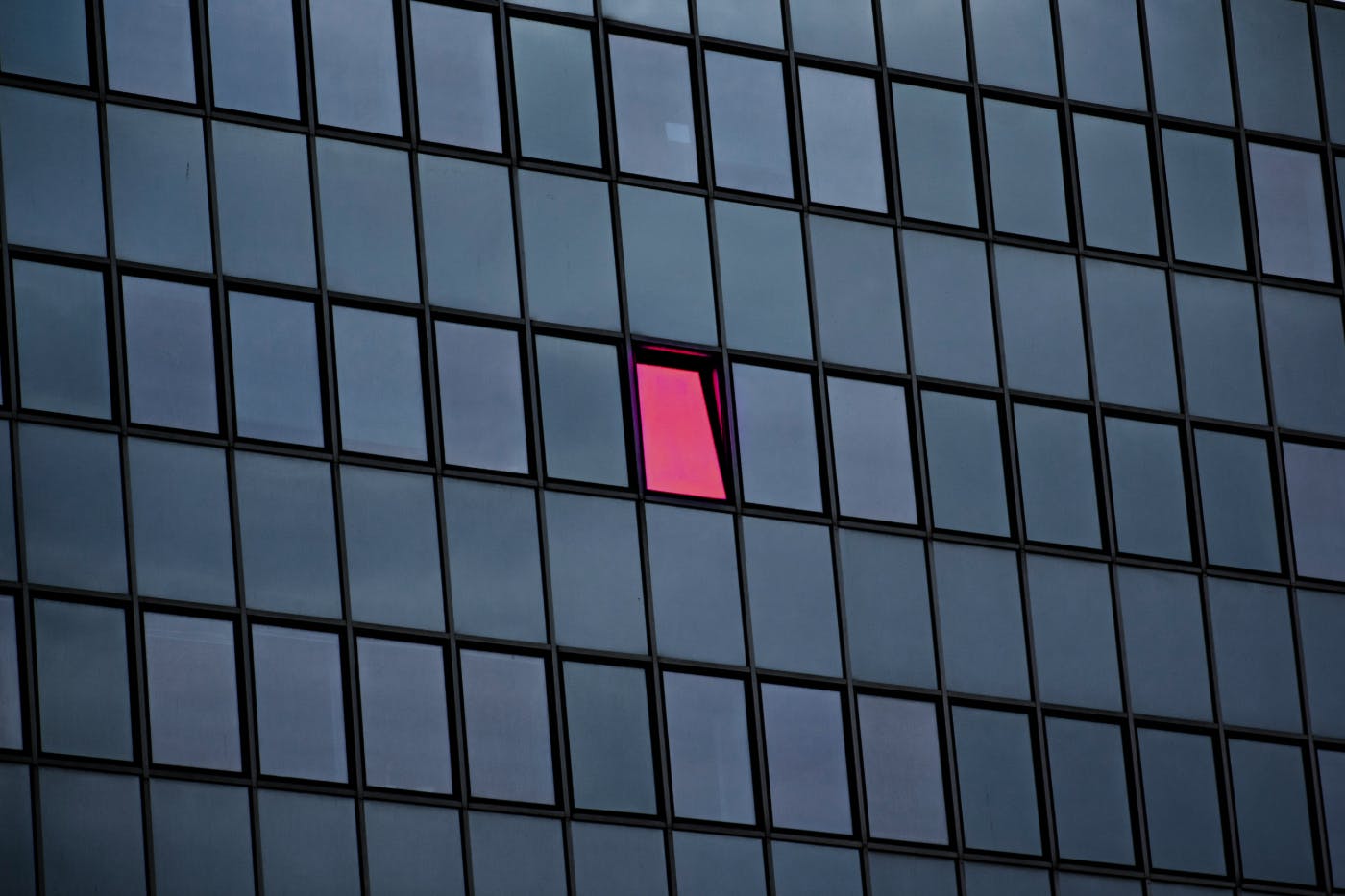 A pink window on a building with grey windows