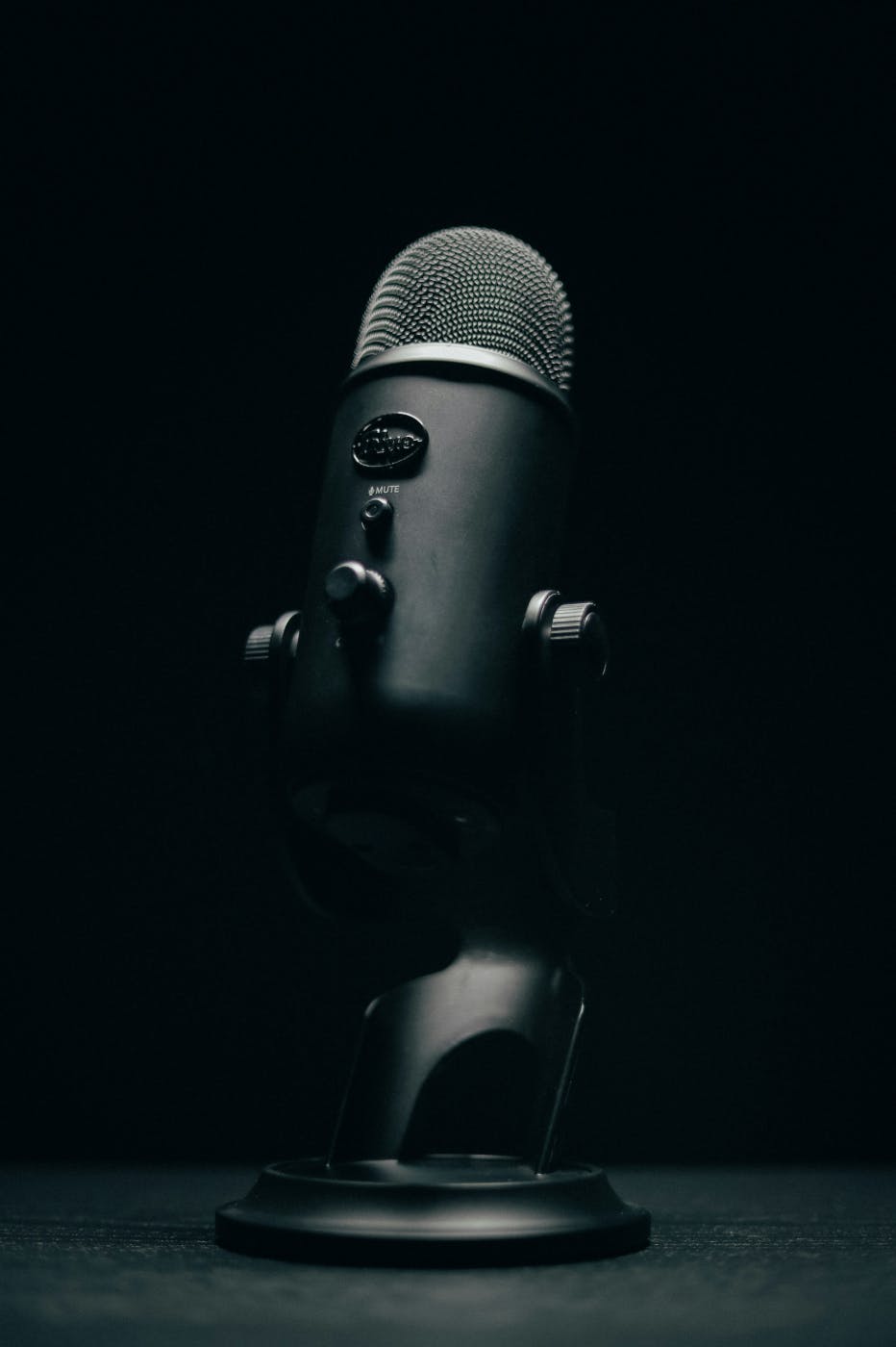 A black microphone on a black table in a dimly lit room