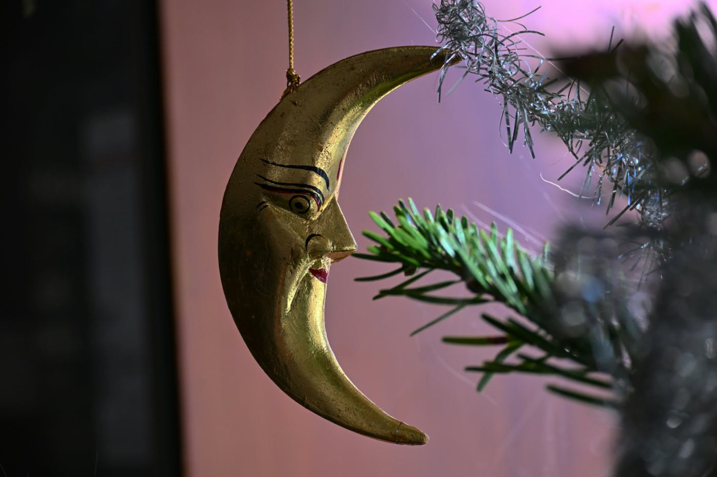 A gold half moon with a face Christmas ornament
