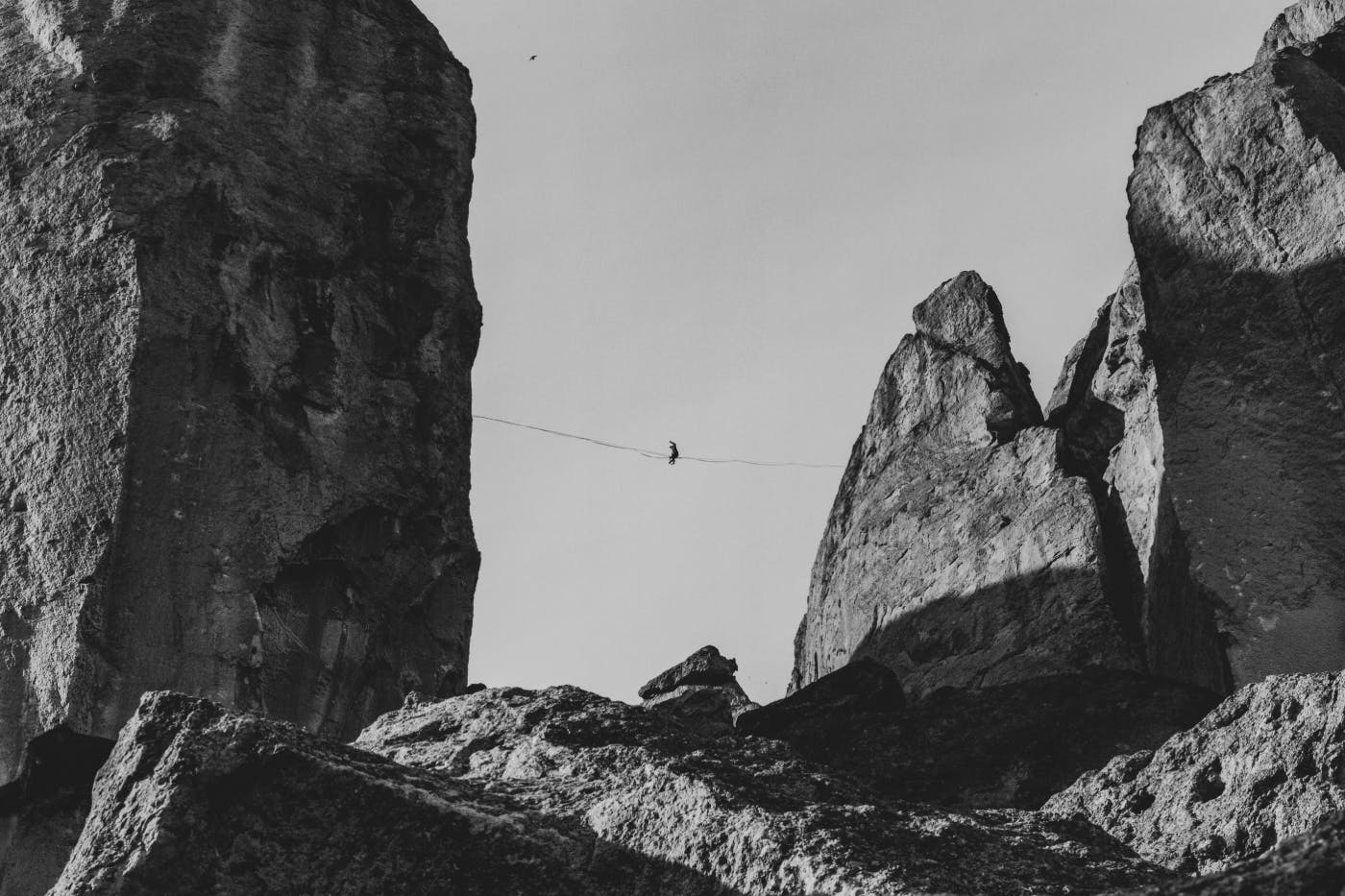 A person high up on a tight rope strung between two rock cliffs