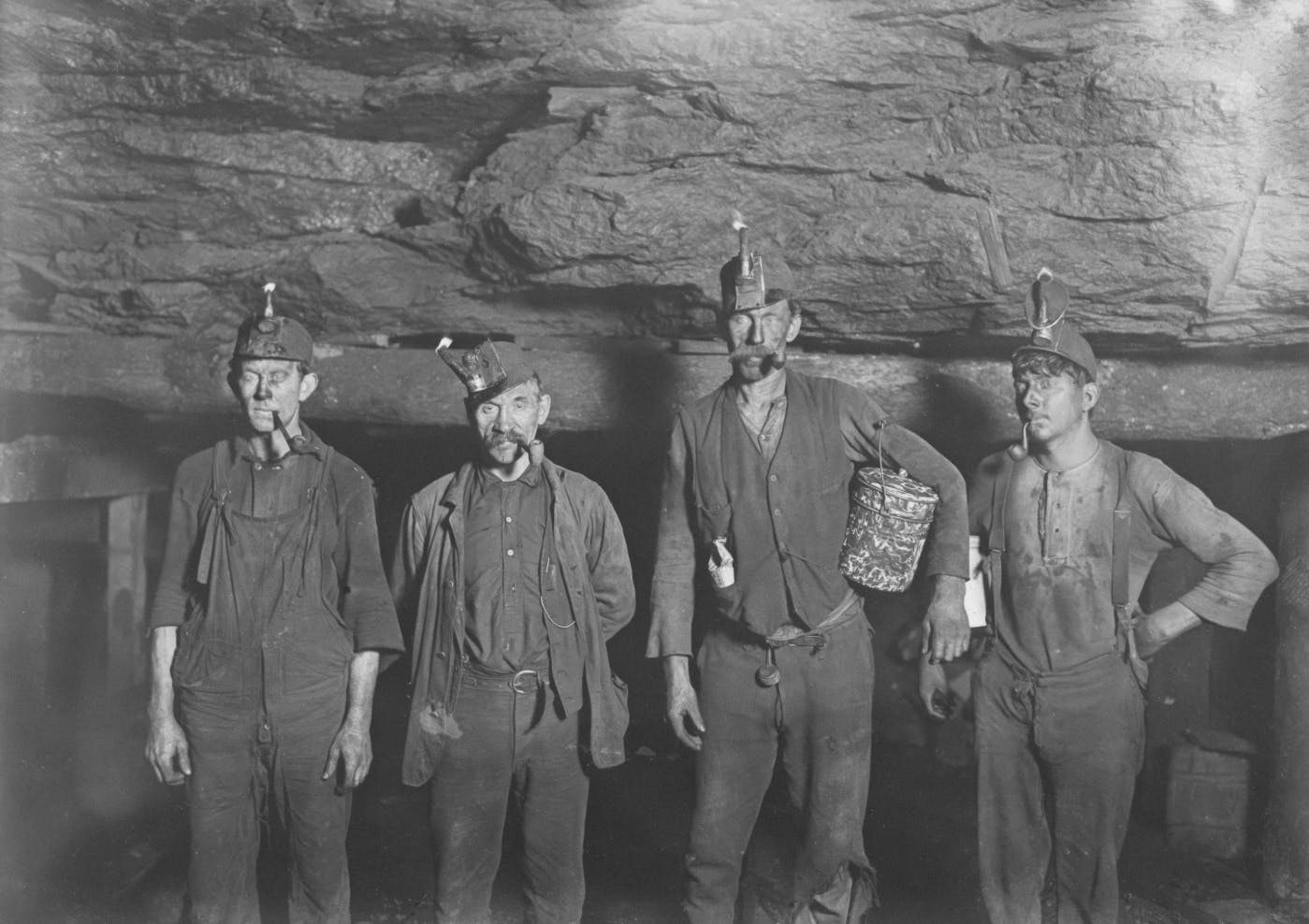 Black and white, miners standing at the opening of a mine