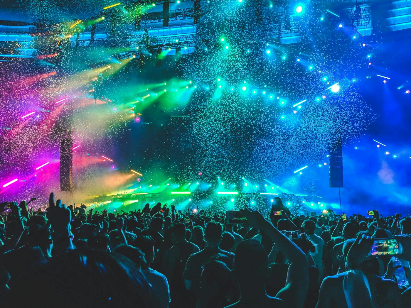 A concert with a huge crowd and lots of colored lights on stage