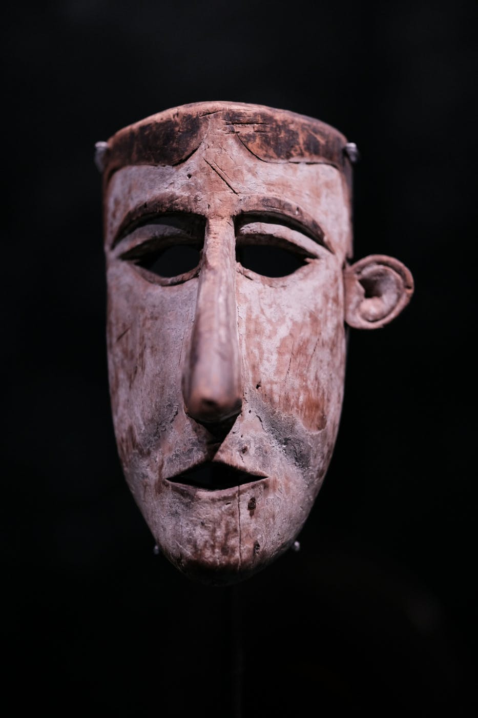 A tribal mask of a man on a black backdrop