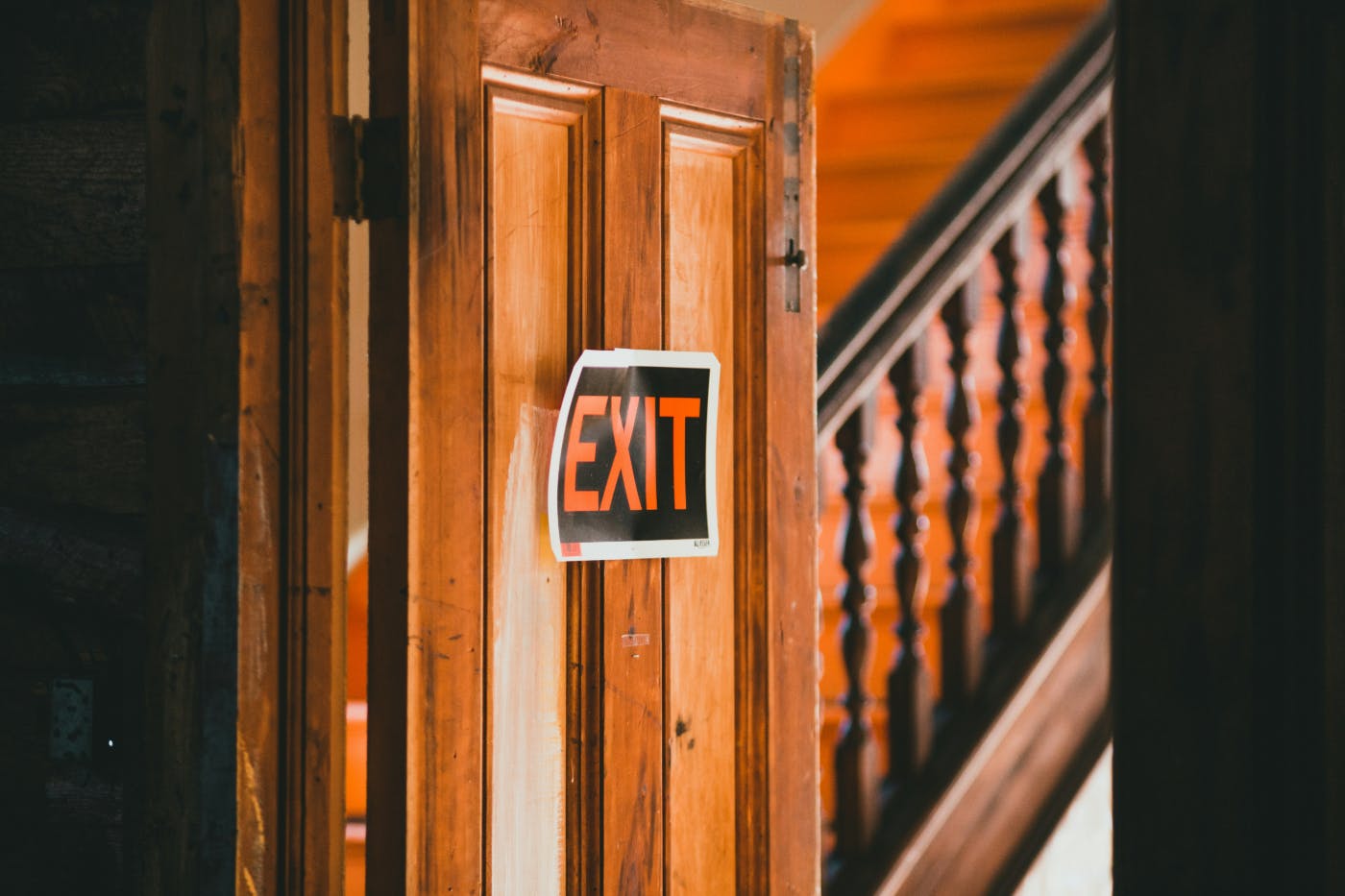 A exit sign posted on a wooden door