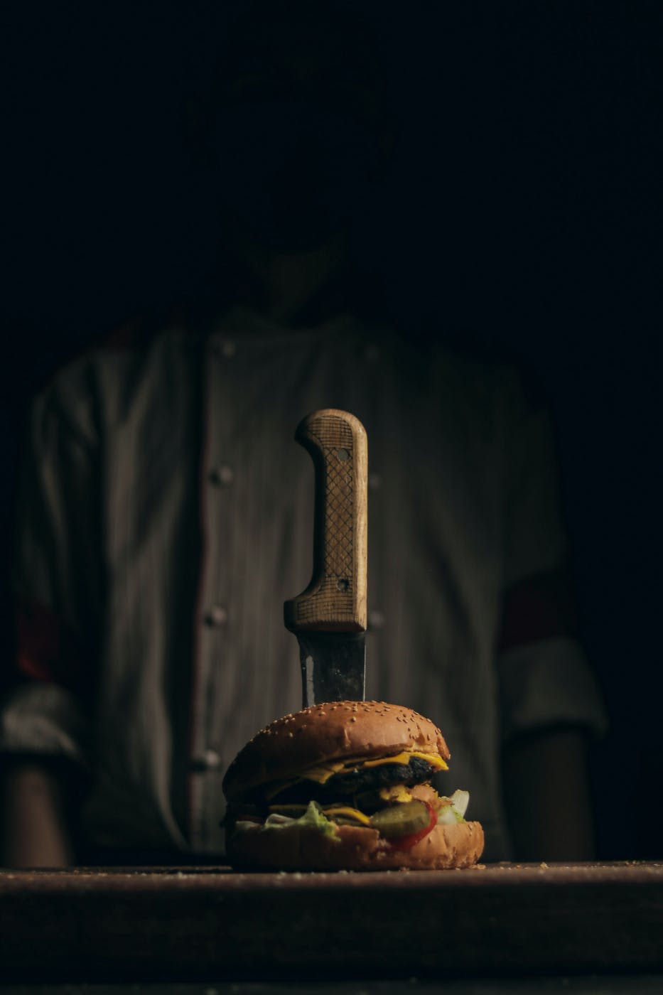 A large burger with a steak knife stuck in it