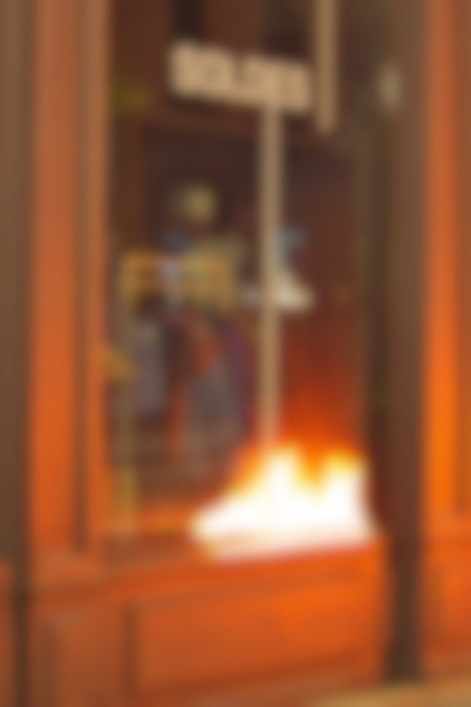 Looking in the window of a French clothing shop, with Soldes (Sale) on the window and the refection of a fire
