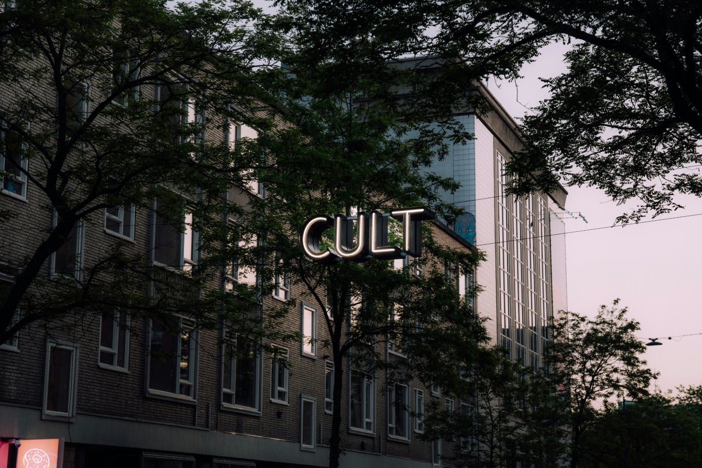 Letters on wires spanning a city street that spell CULT