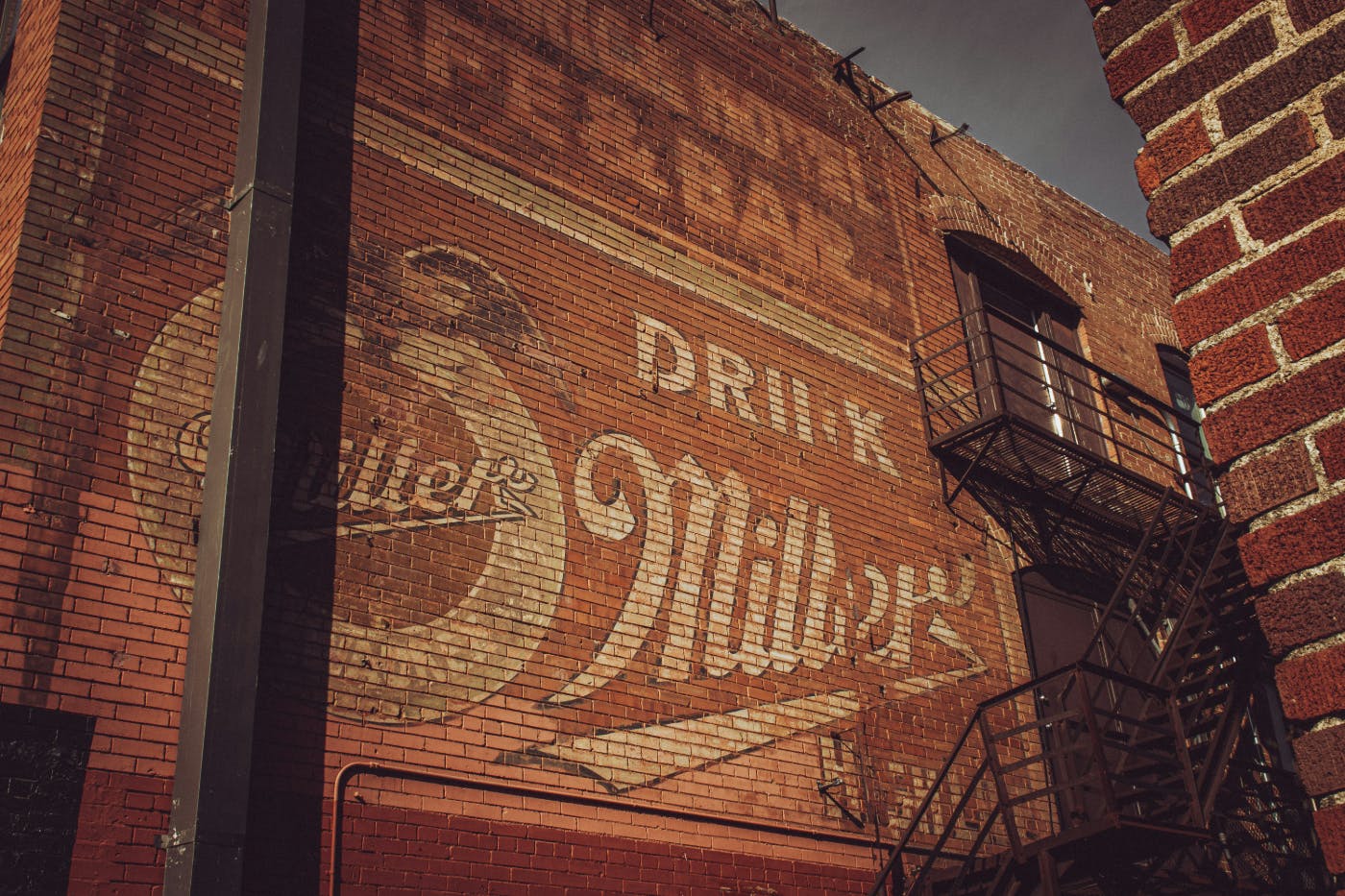 The side of a brick building with a Miller beer and right in the bricks