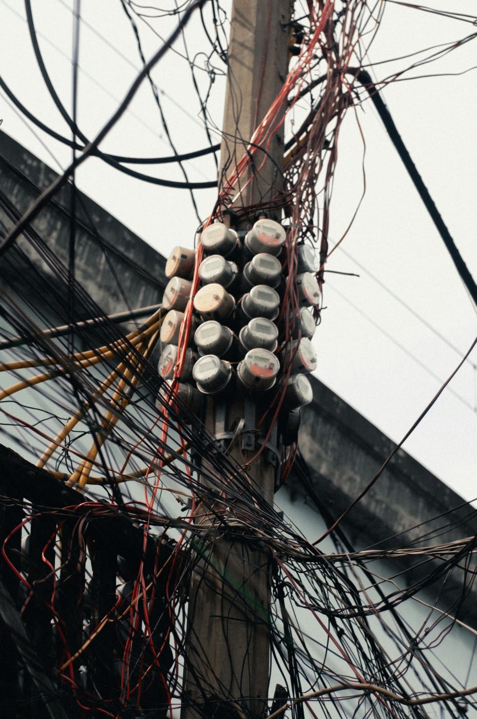 A utility pole with thousands of wires and many meters on it