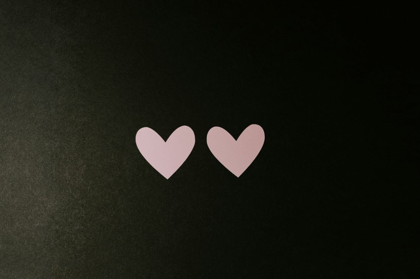 Two pale pink hearts on a black background