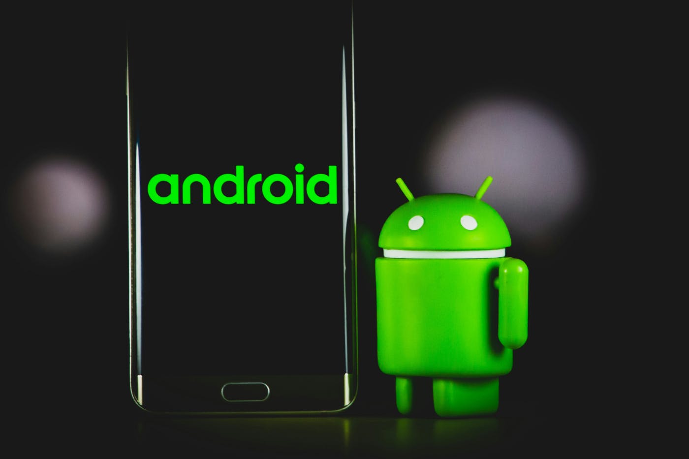 An Android phone next to the little Android mascot