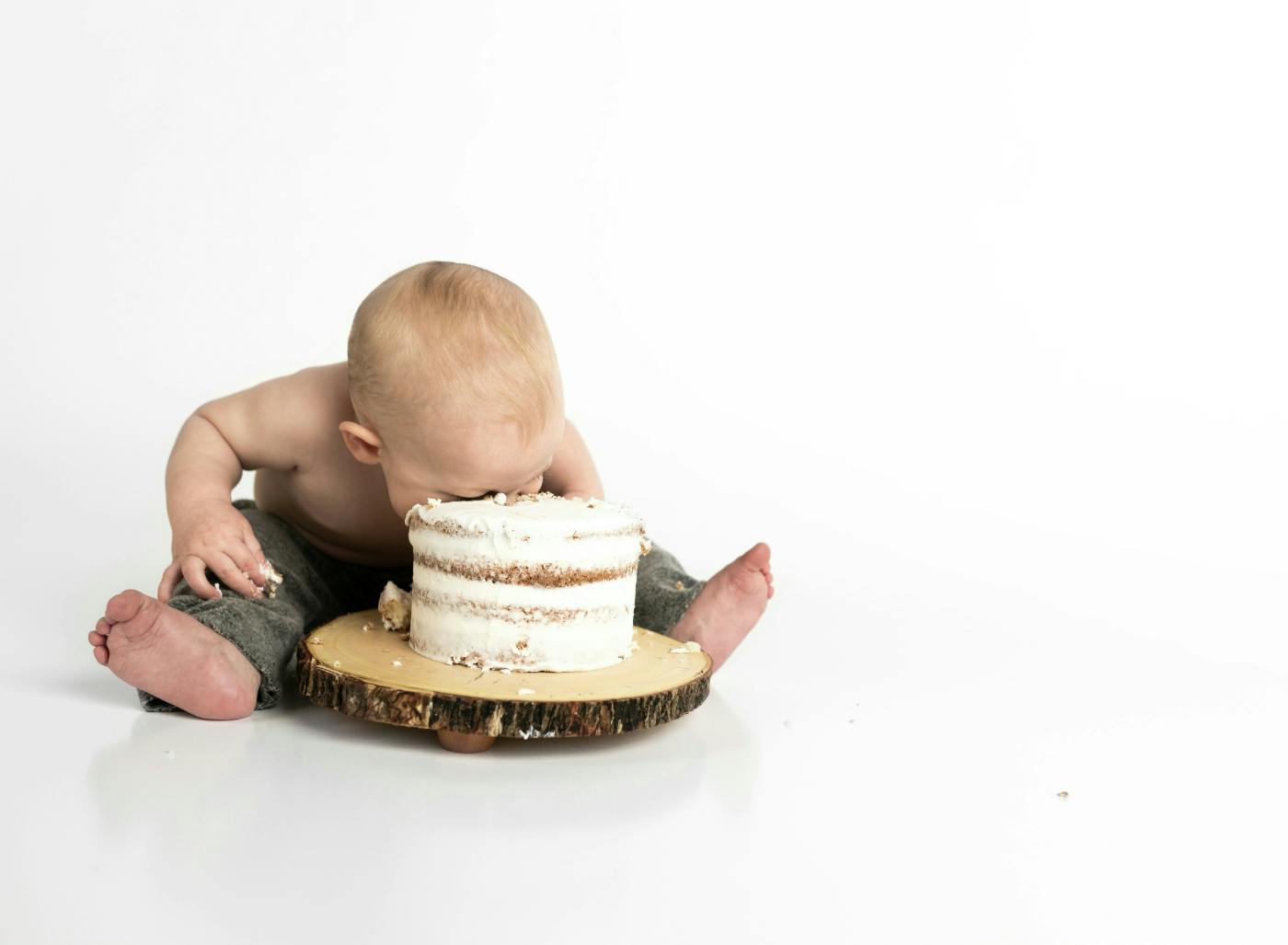 A baby pushing his face into a round cake