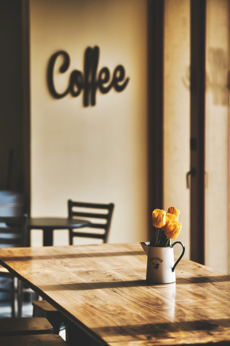 A non-descript cafe with beige walls and tables and the word coffee one the wall