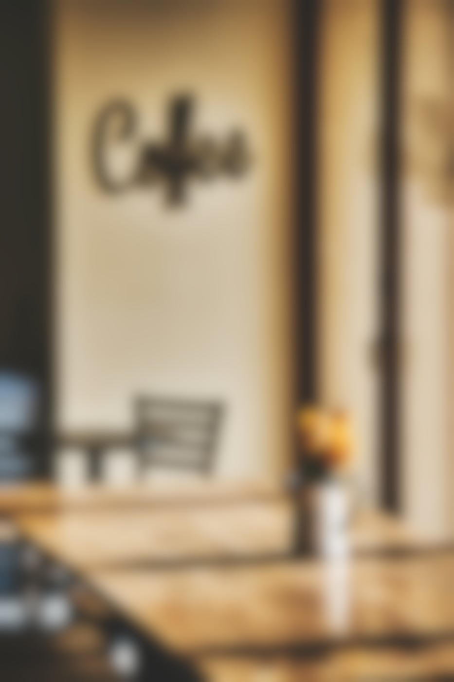 A non-descript cafe with beige walls and tables and the word coffee one the wall